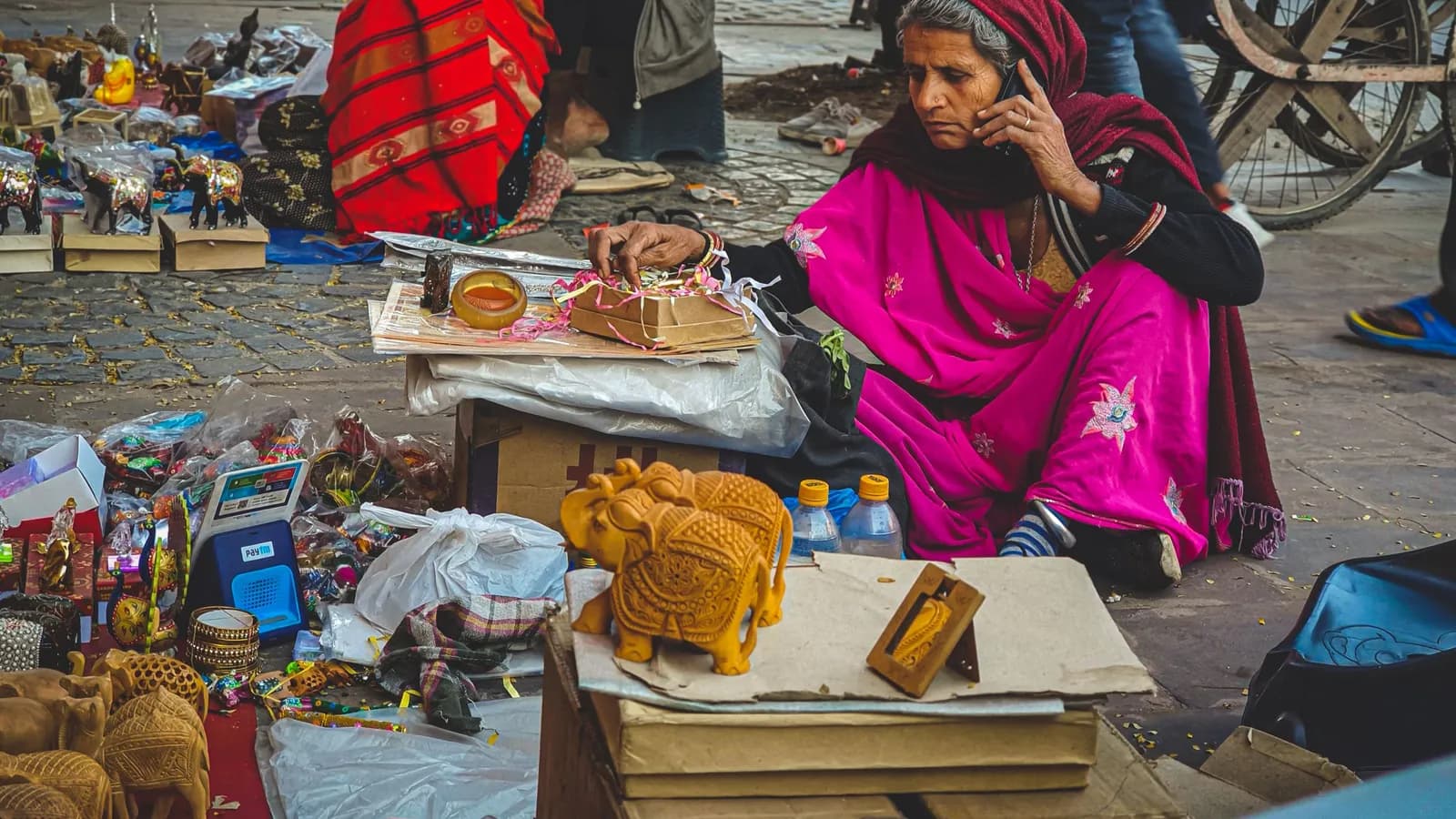 A woman selling handicrafts at a street stall in Jaipur talks on her phone.